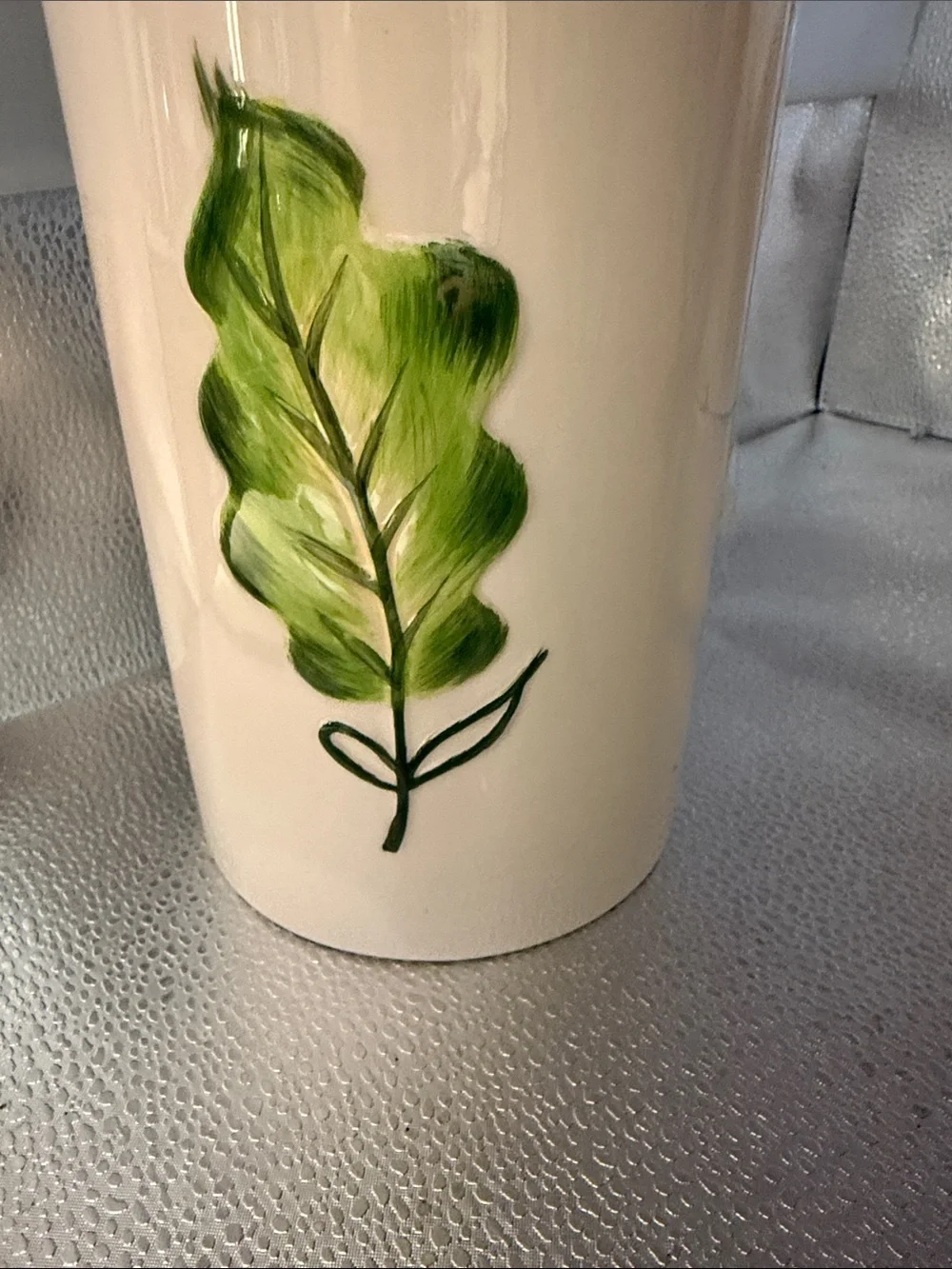 Vintage cylindrical Pier 1 cream canister with a hand painted green leaf
